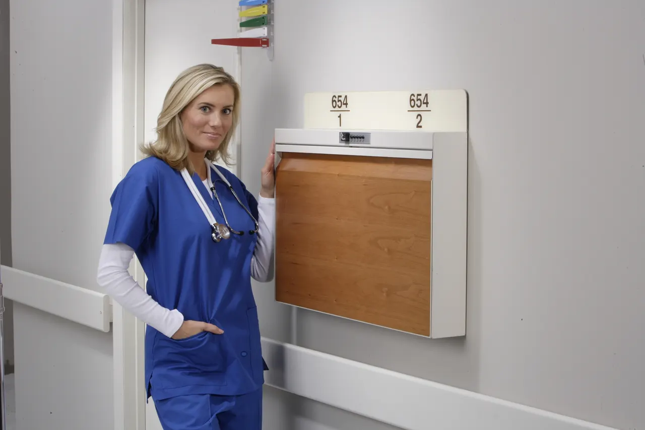 A nurse beside an oak-fronted charting station in a corridor