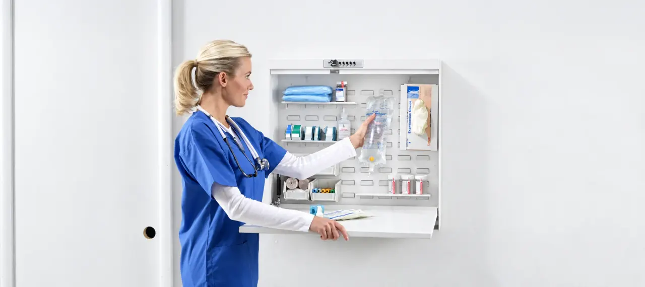A nurse taking supplies from a wall-mounted modular cabinet